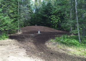 Mound septic system installed by Antlers Well drilling surrounded by trees
